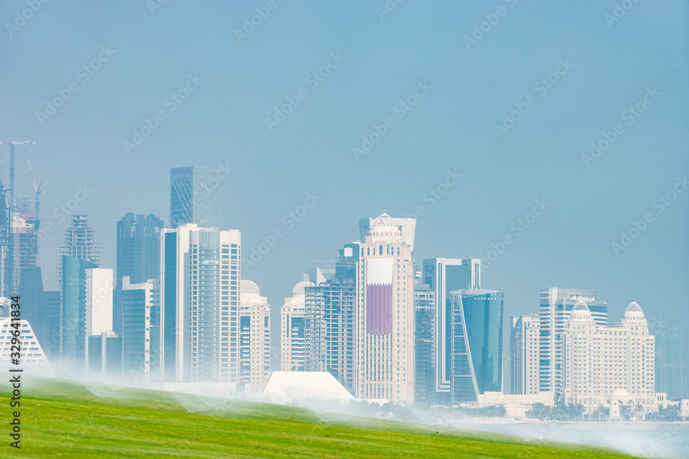 Panoramic view of modern skyline of Doha with green grass foreground. Concept of healthy environment