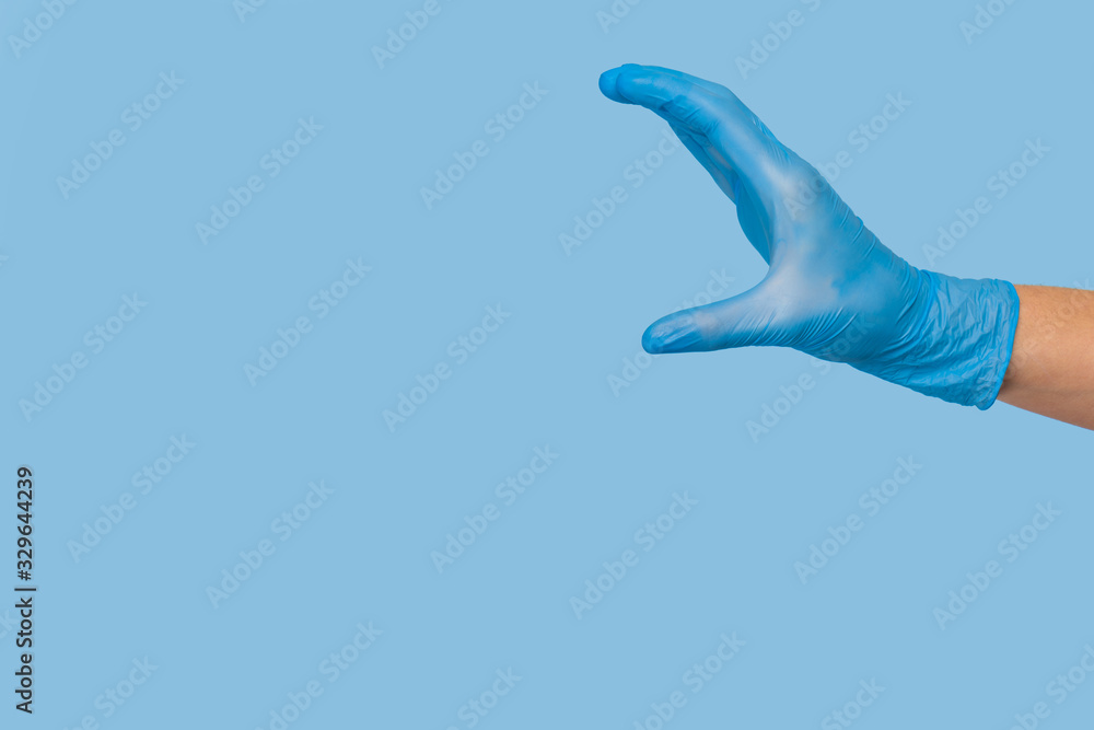 Obraz premium Doctor's hand in a blue medical glove holds an object on a blue background. infection control. mocap, you can insert your product for advertising