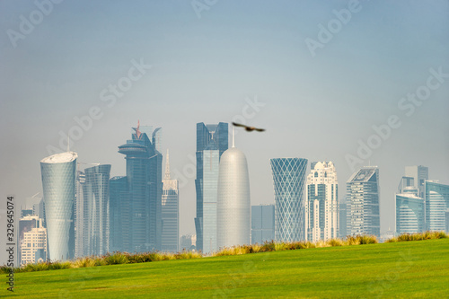 Panoramic view of modern skyline of Doha with green grass foreground. Concept of healthy environment