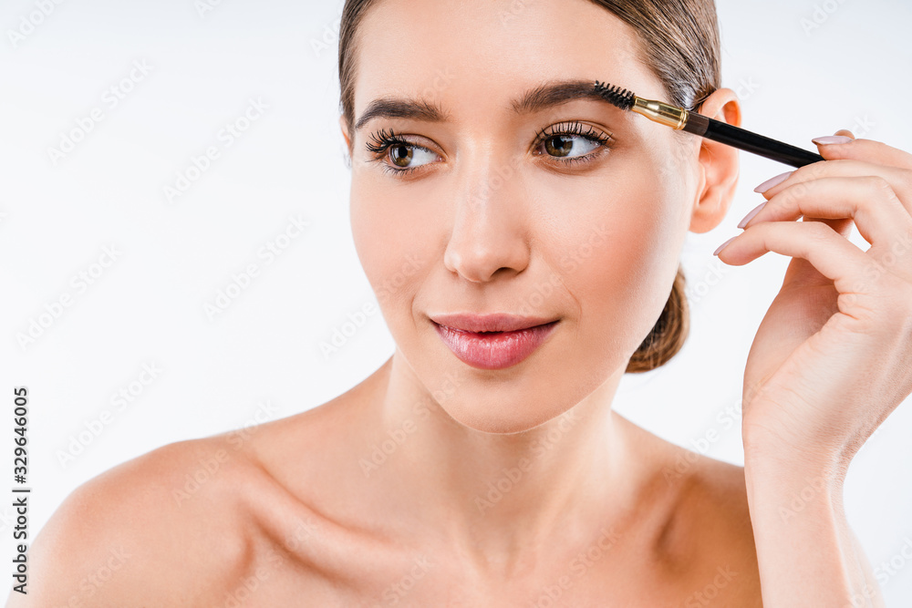 Young beautiful woman applying cosmetic brush on eyebrow, natural makeup on white background Young beautiful woman applying cosmetic brush on eyebrow, natural makeup on white background