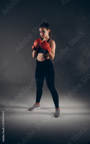 Full-leght Image of a beautiful young amazing sports fitness caucasian woman boxer posing isolated over gray background in red gloves.