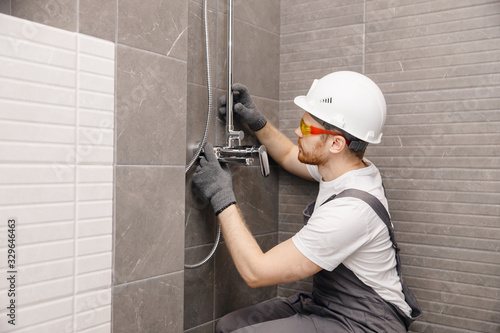 Obraz na plátně Plumber installing water taps shower stall, work in bathroom