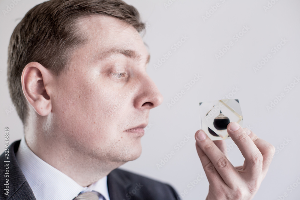 Crying nervous businessman in suit holds in hands and looks to drop of black oil of Brent brand in crystal cube.Crisis in financial market, falling and rising prices, quotes, changes in exchange rate Crying nervous businessman in suit holds in hands and looks to drop of black oil of Brent brand in crystal cube.Crisis in financial market, falling and rising prices, quotes, changes in exchange rate