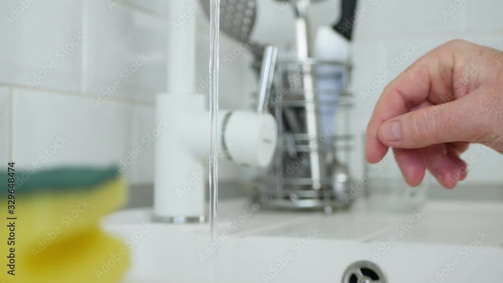 Elderly Person Hand Open Tap Water and Rinse a Dish Sponge in the Kitchen Sink Elderly Person Hand Open Tap Water and Rinse a Dish Sponge in the Kitchen Sink