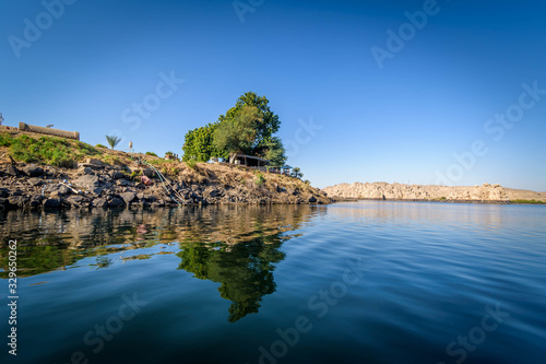 small Rocky island covered with grass and a green tree in the middle of the Nile at Aswan, Egypt