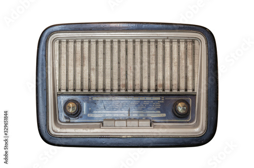An old transistor radio, with knobs and buttons for manual tuning. In the background a vintage wallpaper. Ancient object, worn and ruined by time. Antiques