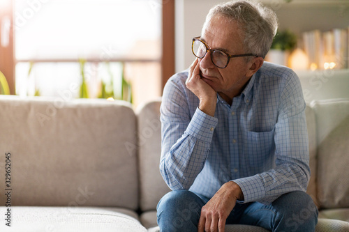 Worried senior man sitting alone in his home photo