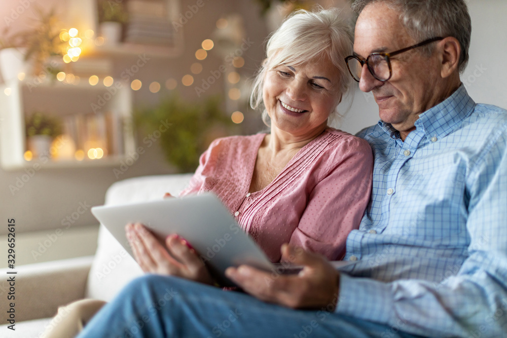 Mature couple using a laptop while relaxing at home Mature couple using a laptop while relaxing at home