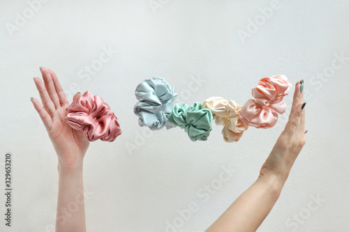 Lot of floating Colorful silk Scrunchies on woma hands isolated white. Hairdressing tools and accessories. Hair Scrunchies, Elastic Hairbands, flying or falling Scrunchies photo