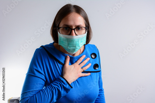 Unhappy brunette woman having breath difficulties in front of white background. A young woman have shortness of breath holding her breast in pain
