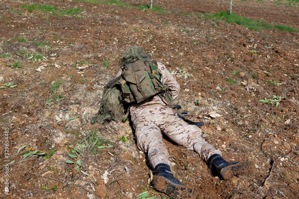 Fototapeta premium soldier with all camouflage gear lying on the ground