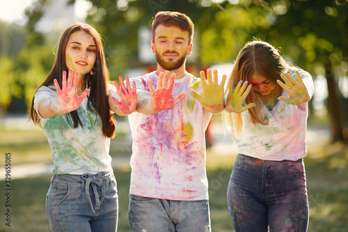 Friends with a holi paints. People in a summer park. Students have fun.