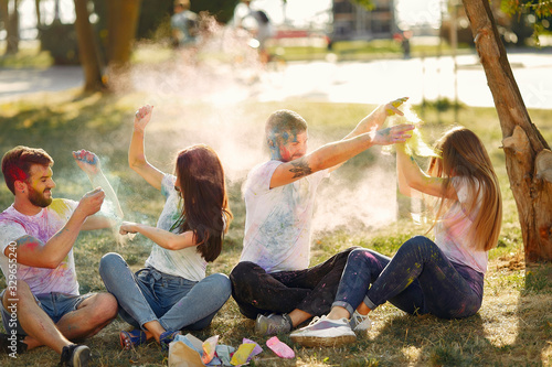 Friends with a holi paints. People in a summer park. Students have fun.