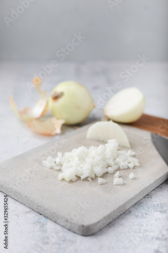Whole and Chopped Yellow Onions on Cement Cutting Board on Cement Countertop