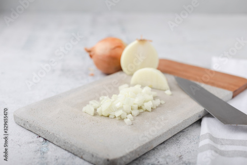 Fotografie Whole and Chopped Sweet Onions on Cement Cutting Board on Cement Countertop