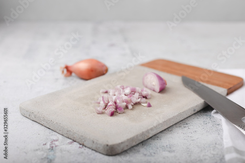Whole and Chopped Shallots on Cement Cutting Board on Cement Countertop