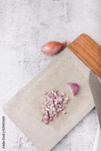 Whole and Chopped Shallots on Cement Cutting Board on Cement Countertop