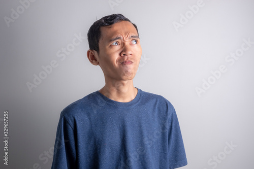 a Young Asian man who is confused thinking about something