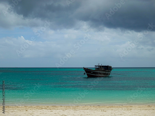Wooden boat off the coast of Zanzibar island, against a background of dark sky and clouds before the rain © Антон Мазаев