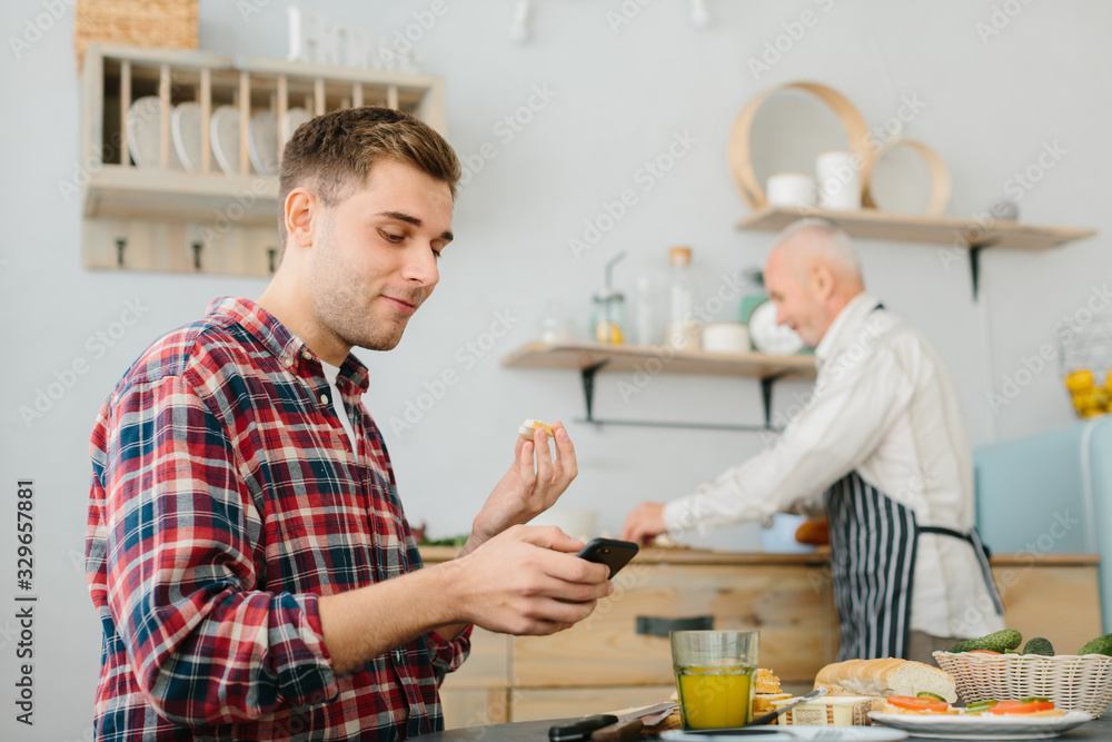 Young man and his father cooking in kitchen Young man and his father cooking in kitchen
