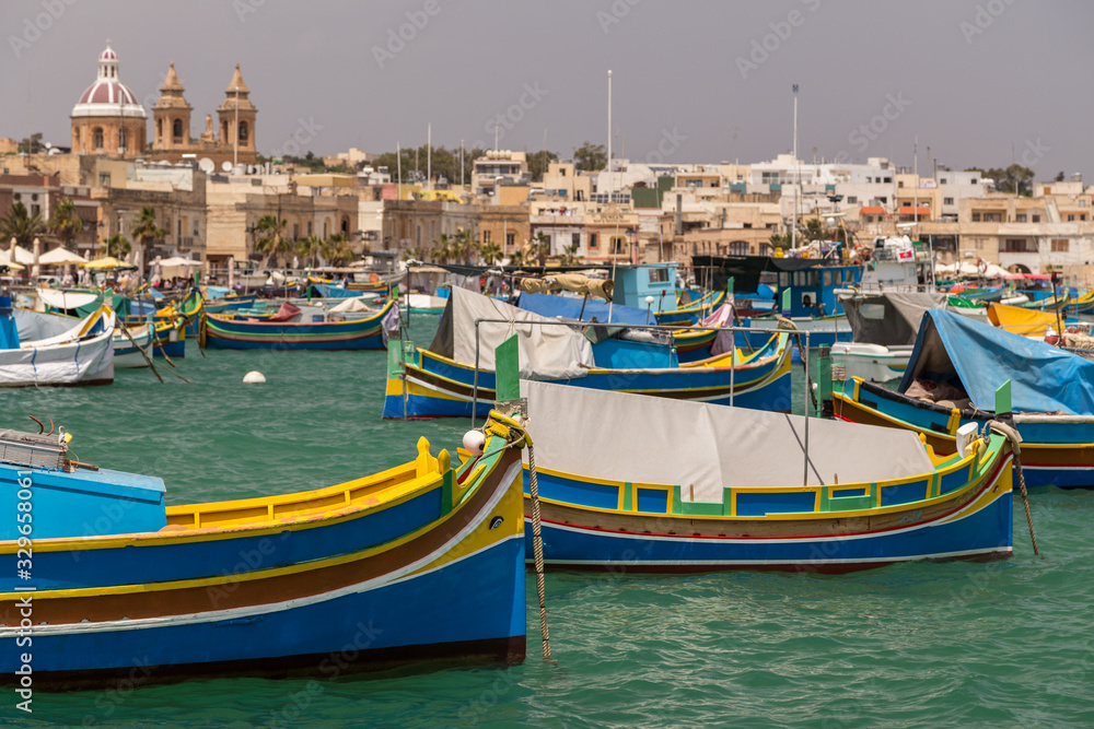 Fishing boats in the harbour and buildings of Marsaxlokk, Malta