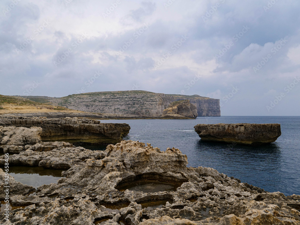 The stone coast on the island of Malta and pieces of rock in the waters of the Mediterranean Sea