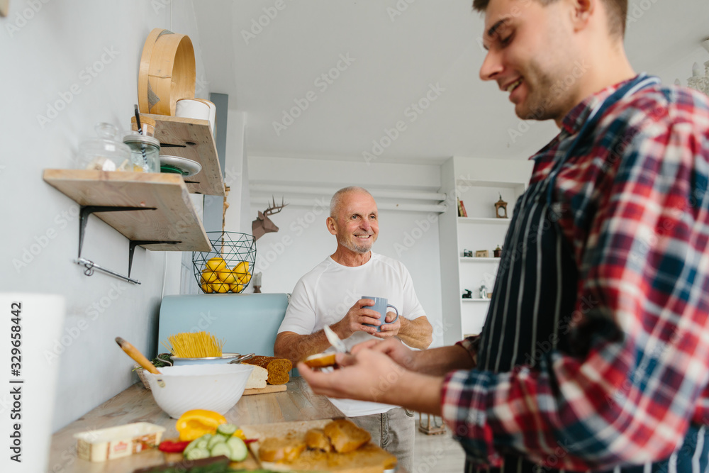 Young man and his father cooking in kitchen Young man and his father cooking in kitchen