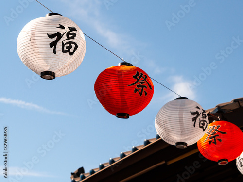 Paper lanterns blowing in the wind in Little Tokyo at sunset with clouds. A statue of a fish located on the roof of a house. Los Angeles California.