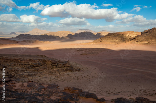 Kingdom of Jordan  Wadi Rum desert  sunny winter day scenery landscape with white puffy clouds and warm colors. Lovely travel photography. Beautiful desert could be explored on safari. Colorful image