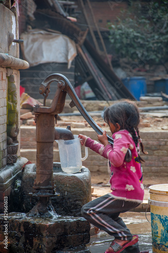 Little girl getting water from the pump