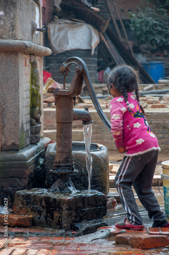 Little girl getting water from the pump