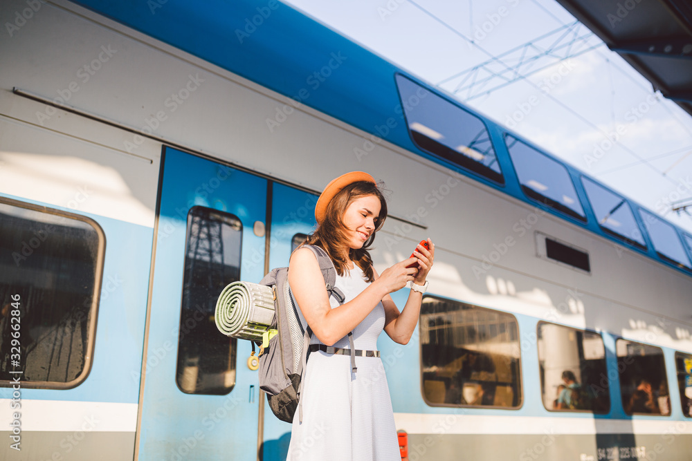 Smiling woman using smart phone on station. Young woman holding ...