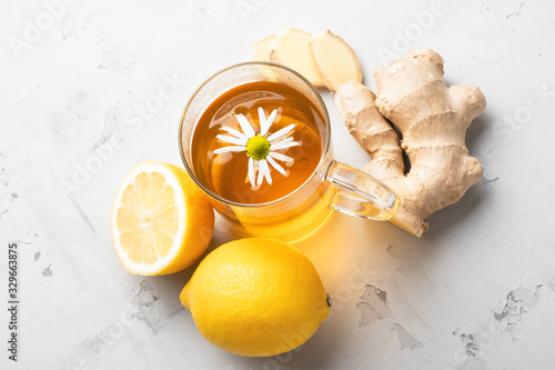 Alternative medicine, natural home remedy for cold and flu. Hot herbal tea with camomile, ginger and lemon photo