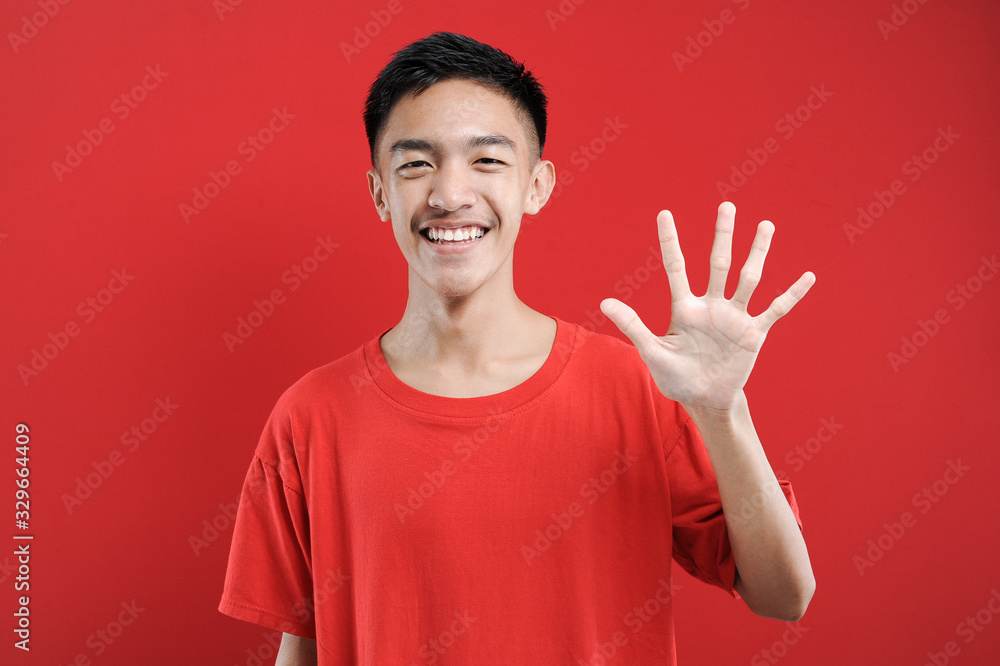 Young Asian man with number five sign finger gesture Young Asian man with number five sign finger gesture