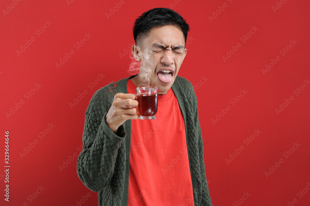 Young Asian man drinking a cup of bad tea, bitter tea Young Asian man drinking a cup of bad tea, bitter tea