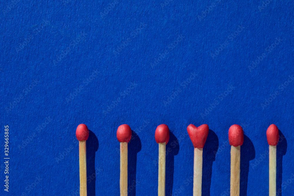 Matchsticks with a red heads with heart shaped match among others on a classic blue background. Concept of perfect match, fire of love and passion. The one and only. Flat lay, top view and copy space. Matchsticks with a red heads with heart shaped match among others on a classic blue background. Concept of perfect match, fire of love and passion. The one and only. Flat lay, top view and copy space.