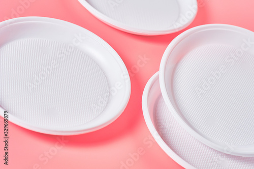 Disposable plastic plates scattered on pink background. Concept of save environment, ecology, recreation on picnic, party and other events