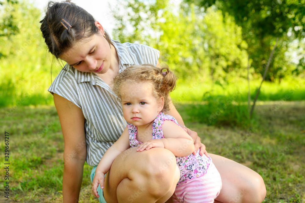 mom plays with her cute little one year old daughter with curly hair. family with little children have fun spending summer holidays in nature outdoor mom plays with her cute little one year old daughter with curly hair. family with little children have fun spending summer holidays in nature outdoor