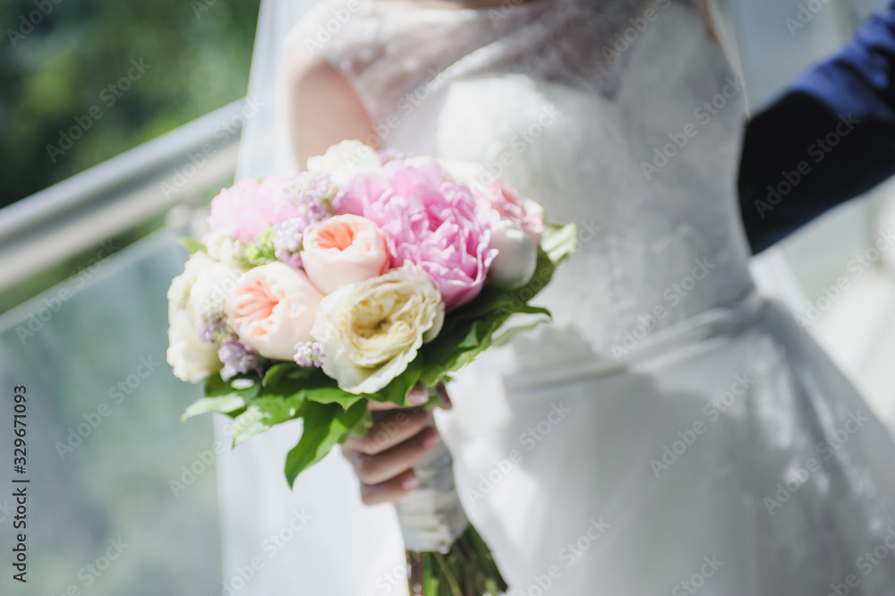 beautiful modern wedding bouquet in bride's hand. Girl in a white wedding dress. Love and tenderness.