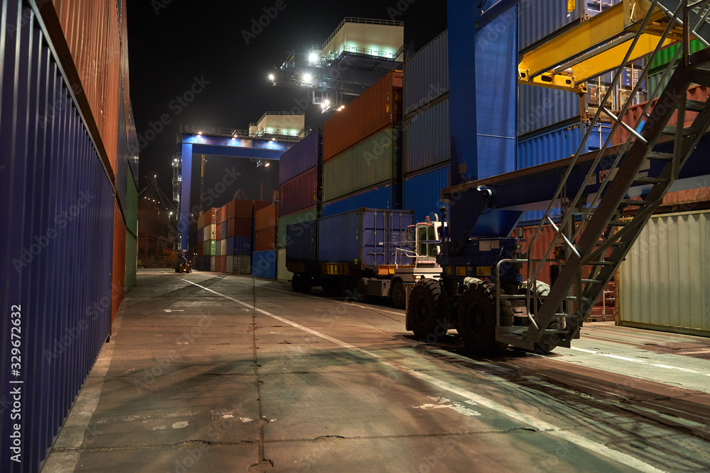 Naklejka premium operation of container terminal at night. Unloading container ship at night. Mooring cranes unload container ship at night