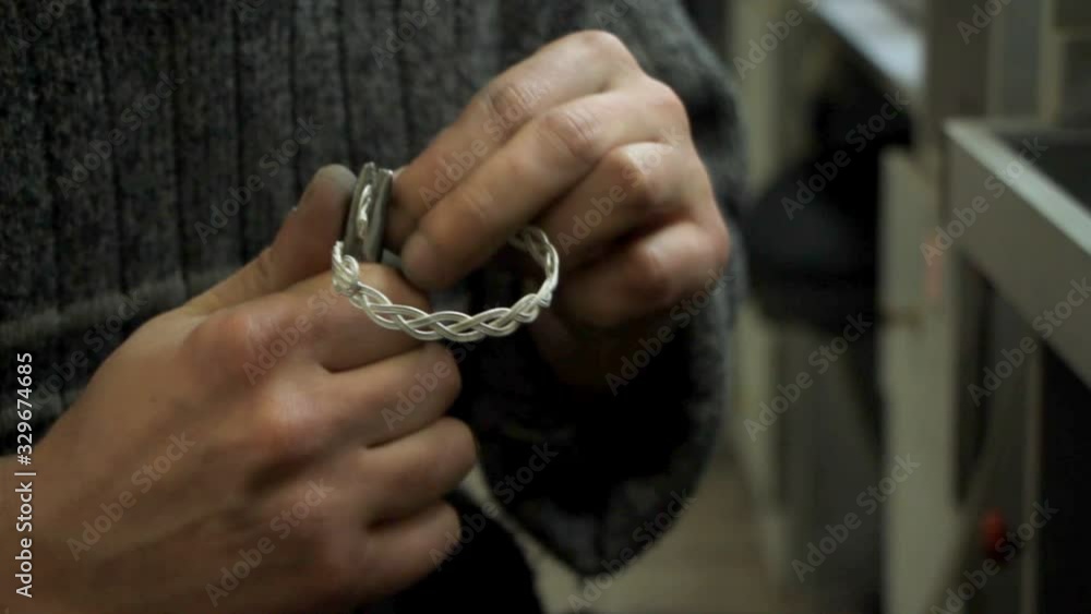 The master jeweler holds the working tool in his hands and makes jewelery at his workplace The master jeweler holds the working tool in his hands and makes jewelery at his workplace