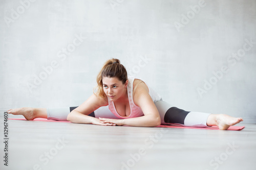 Lovely woman doing stretching or yoga exercise on a mat