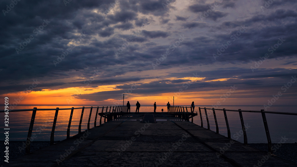 Pier fishermen at sunset dark clouds