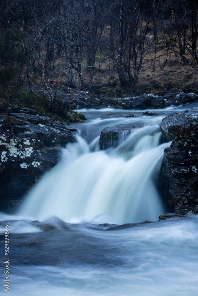 the waterfalls in Glen Orchy near Bridge of Orchy in the Argyll region of the highlands of Scotland during winter whilst the river is flowing fast from rainfall the waterfalls in Glen Orchy near Bridge of Orchy in the Argyll region of the highlands of Scotland during winter whilst the river is flowing fast from rainfall