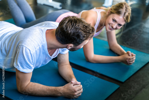 Sport men and women exercise planking on yoga mat in sport gym together