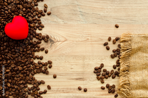 Fragrant coffee beans, decorative red heart, pouch. Wooden background. Place for text.