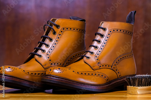 Male Fashionable Footwear Concepts. Pair of Tanned Calf Leather Derby Brogues Placed Together With Cleaning Brush Indoors