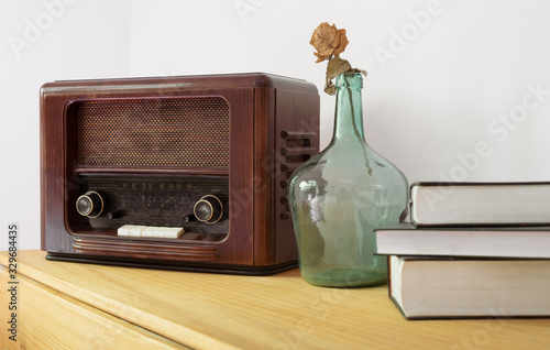 Vintage radio made of wood, green vase and old books on a table