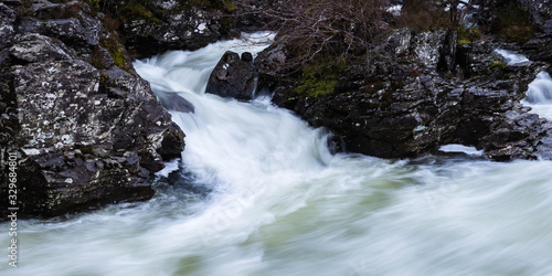 Fototapeta Naklejka Na Ścianę i Meble -  the waterfalls in Glen Orchy near Bridge of Orchy in the Argyll region of the highlands of Scotland during winter whilst the river is flowing fast from rainfall