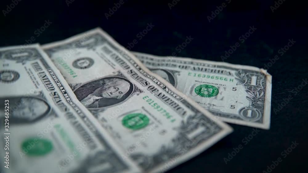 American one-dollar banknotes falling on dark table top in slow motion. American one-dollar banknotes falling on dark table top in slow motion.
